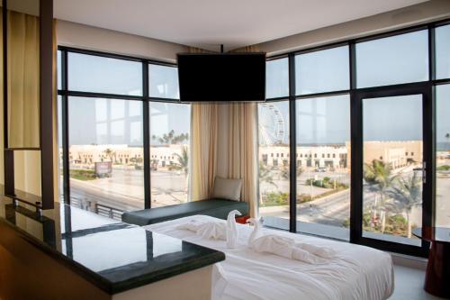 a hotel room with a bed and a large window at Souq Beach Hotel فندق سوق الشاطئ in Salalah