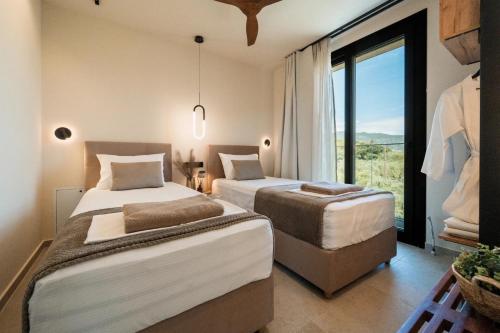 two beds in a room with a large window at Ammosphere in Nea Peramos
