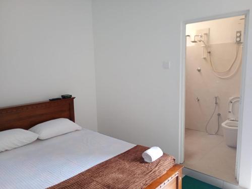 a bedroom with a bed and a bathroom with a shower at Eco Bliss Ragama in Ragama