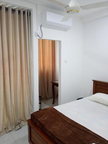 a bedroom with a bed and a window with curtains at Eco Bliss Ragama in Ragama
