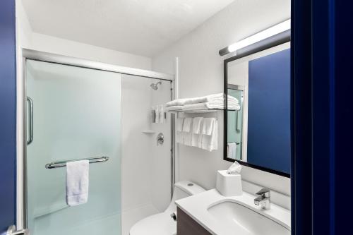 a bathroom with a shower and a sink and a mirror at Spark By Hilton Beckley in Beckley