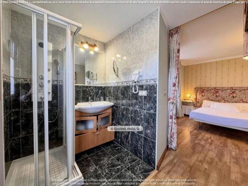 a bathroom with a shower and a sink and a bed at Hotel Vitorio in Cudillero