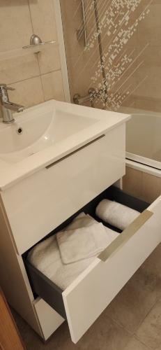a white bathroom with a sink and a tub at Chez Nathalie - Appartement cosy- Multi pass offert- Draps, serviettes et ménage compris in Saint-Jean-d'Aulps