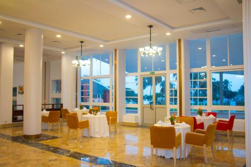 ein Esszimmer mit Tischen, Stühlen und Fenstern in der Unterkunft LEBENE Hotel in Lomé