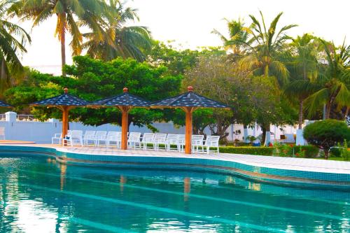 ein Swimmingpool mit Liegestühlen und Sonnenschirmen in einem Ferienresort in der Unterkunft LEBENE Hotel in Lomé