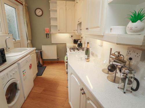 a kitchen with white cabinets and a washer and dryer at The Haven in Morecambe