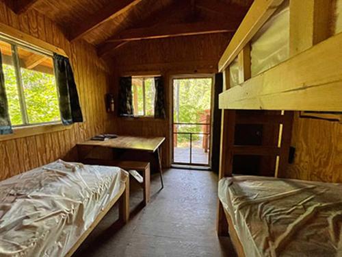 a bedroom with two beds and a desk in a cabin at Timber Wolf Campground Resort & Jeep Rentals in Hungry Horse