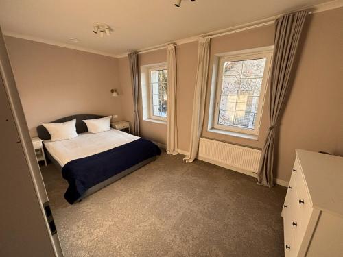 a bedroom with a bed and two windows at Szafirowy Dwór Hotel & Restauracja in Gliwice
