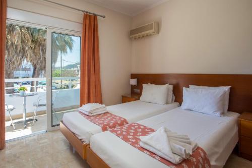 two beds in a hotel room with a balcony at Perla Marina Hotel in Ialysos