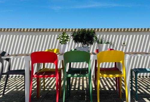 a table with colorful chairs in front of a fence at BRIC à BRAC eclectic rooms in Uggiano la Chiesa
