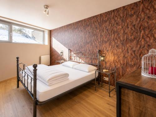 a bedroom with a metal bed and a wooden wall at Au Bailet in Gedinne