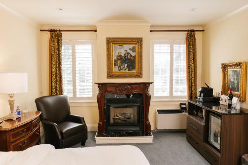 a living room with a fireplace and a chair at Riverbend Inn & Vineyard in Niagara-on-the-Lake