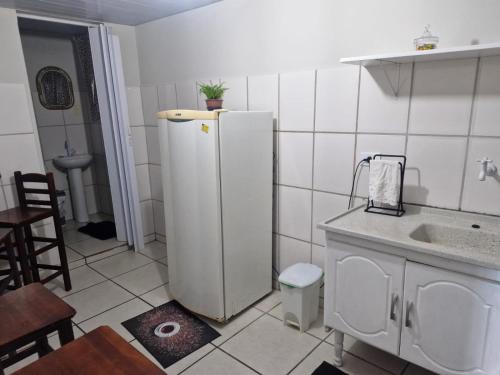 a kitchen with a white refrigerator and a sink at Flat Casa Grande in Itapira