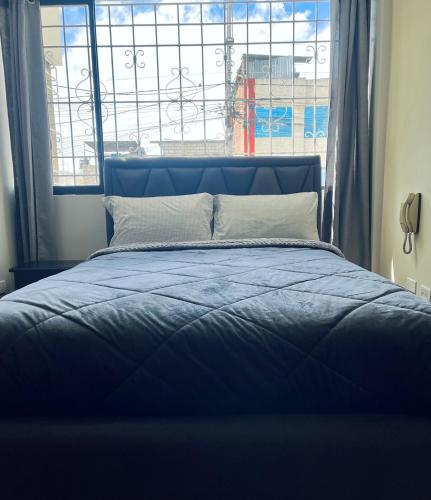 a blue bed in a room with a window at Centrica y Residencial in Ambato