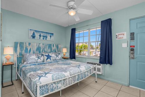 a bedroom with a bed with blue walls and a window at Latitude 26 Waterfront Boutique Resort - Fort Myers Beach in Fort Myers Beach