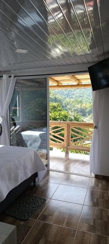 a bedroom with a bed and a balcony with a view at La cabañita VIP in Minca