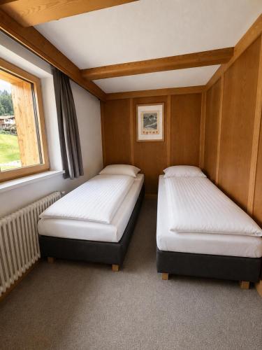 two beds in a small room with a window at Demlhof, Gästehaus in Finkenberg