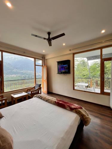 a bedroom with a bed and a tv on the wall at Nomad House in Manāli