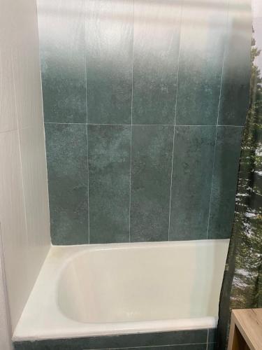 a white bath tub with a green tiled wall at Apartament Tudor in Făgăraş