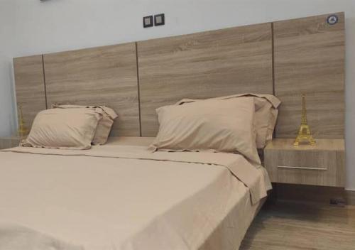 a bedroom with a large white bed with a headboard at STUDIO Meublée à Gbodjè in Porto-Novo
