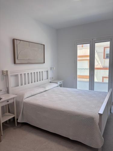 a white bedroom with a large bed and a window at La LLar in Carboneras