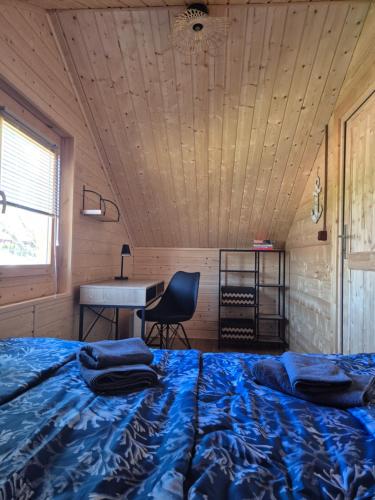 a bed in a room with a desk and a table at Domek pod Wierzbami in Leleszki