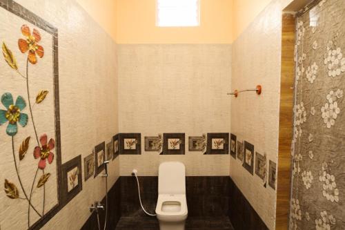 a bathroom with a toilet and pictures on the wall at Malar Resort in Wodapatti