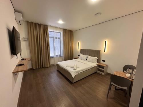 a bedroom with a bed and a desk and a television at Gatsby Djal in Bishkek