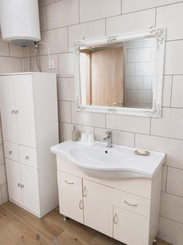 a white bathroom with a sink and a mirror at Apartma PERIN in Dobrovo