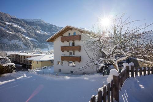 a building with snow on the ground next to a fence at Garni Nill in Schwendau