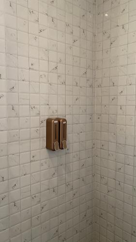 a white tiled bathroom with a soap dispenser on the wall at Defano Villa Klotok in Yogyakarta