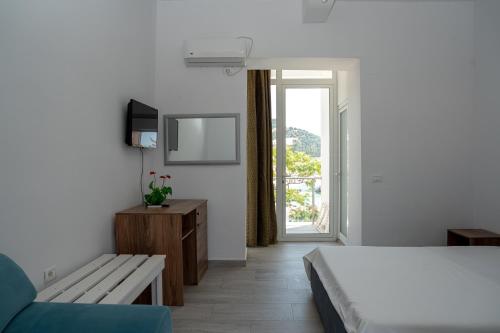 a bedroom with a bed and a couch and a window at Hotel Riviera Dhermi in Dhërmi