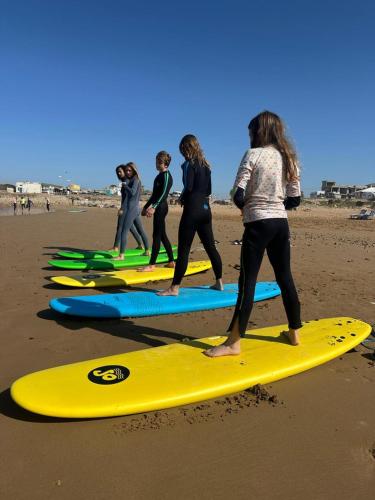 a group of people standing on surfboards on the beach at ,,,''' Sidi kaouki Tayoukhte Surf House with Pool ''' ,,, Surfing lessons, Horse Riding & Quad adventures ,,, Local experiences all in one place in Sidi Kaouki