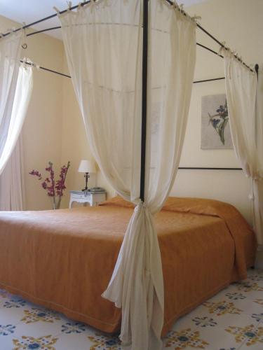 a bedroom with a canopy bed with white curtains at Hotel Bougainville in Lipari