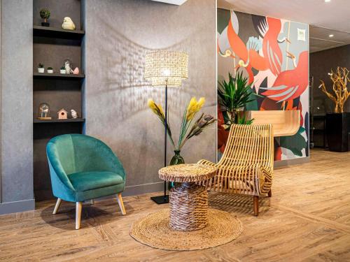 a room with two chairs and a table and a lamp at ibis Styles Rennes Cesson in Cesson-Sévigné