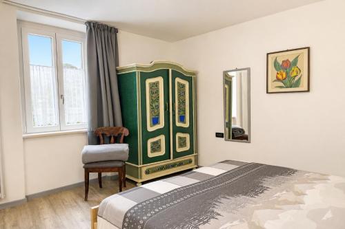 a bedroom with a bed and a chair and a mirror at All'antica Birreria in Predazzo