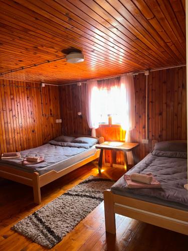 two beds in a wooden room with a window at Ljubav Stara Zaovine in Lazići