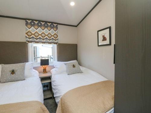 two beds in a room with a desk and a window at Hollybirch in Crieff