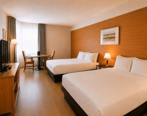 a hotel room with two beds and a table at Hôtels Gouverneur Rimouski in Rimouski