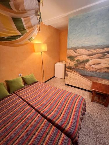 a bedroom with a bed and a painting on the wall at Pensión El Alamo in Lepe