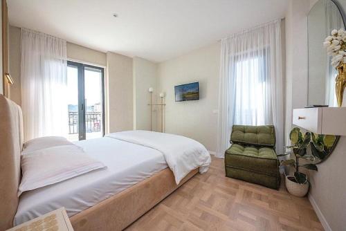 a bedroom with a large bed and a chair at Green Terrace Square View in Tirana