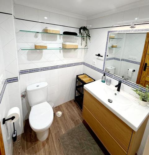 a white bathroom with a toilet and a sink at Apartamento SOLYMAR Chipiona in Chipiona