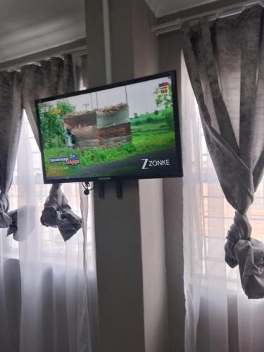 a flat screen tv sitting in a window with curtains at Tourist Guest House Accommodation in Mahikeng