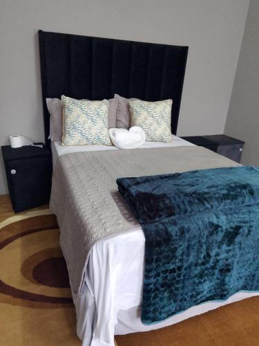 a bedroom with a large bed with a blue blanket at Tourist Guest House Accommodation in Mahikeng
