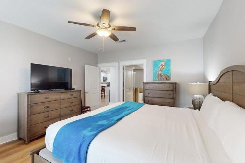 a bedroom with a large bed and a ceiling fan at Sand Swept in Galveston