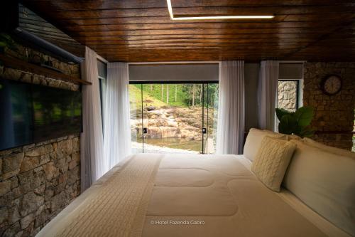 a bed in a room with a large window at Hotel Fazenda Gabro - Vitra in Apiaí