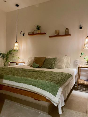 a bedroom with a large bed with a green blanket at Casa Arena Cozumel in Cozumel
