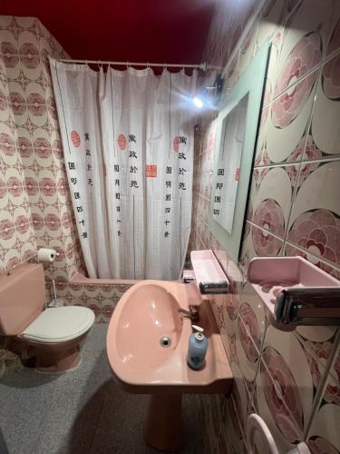 a bathroom with a pink sink and a toilet at Pensión El Alamo in Lepe