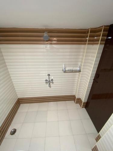 a bathroom with a shower with a tile floor at Umbrella Comfy Stays-Subbu in Madurai