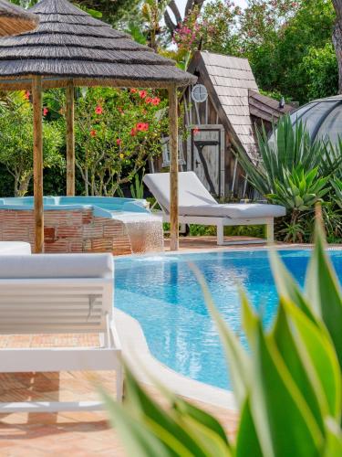 a swimming pool with two chairs and a gazebo at Villa CHELSEA in Vilamoura